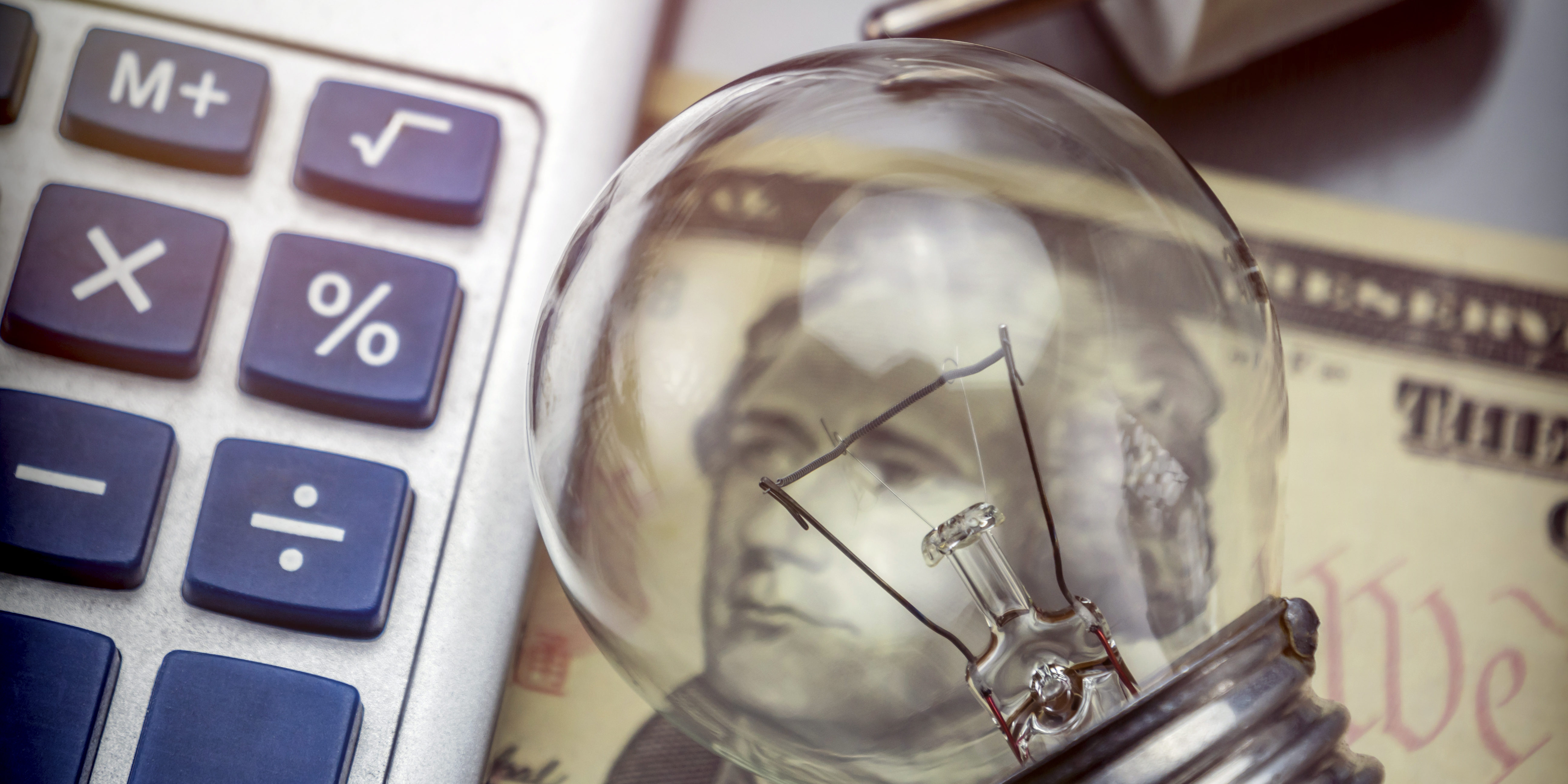 Calculator and money next to a light bulb, the concept of energy saving