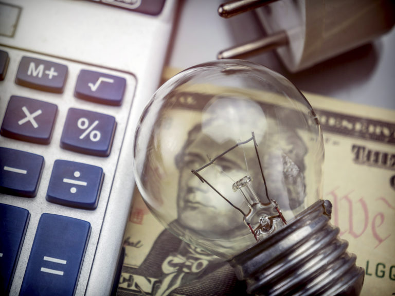 Calculator and money next to a light bulb, the concept of energy saving