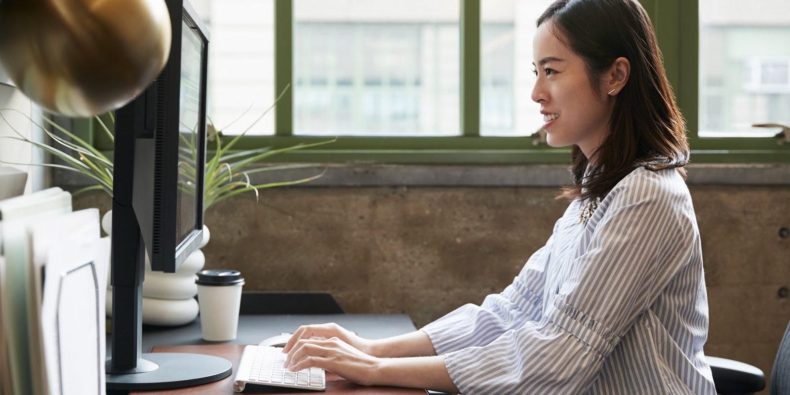 Chinese woman working at a computer in an office, side view