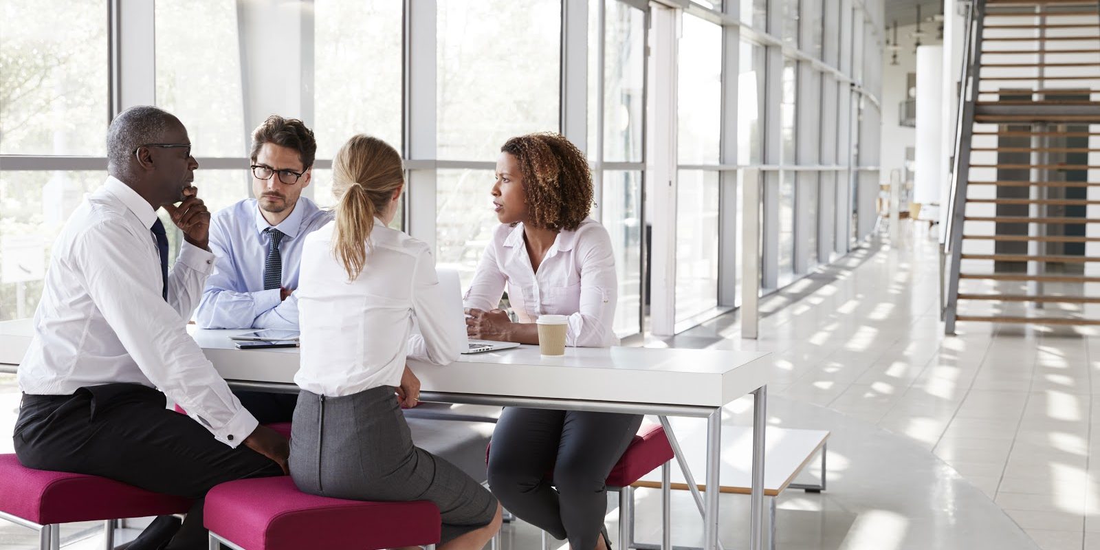 Young business people talking in modern lobby, full length